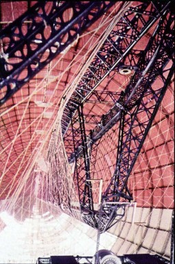 Interior of hull of Hindenburg sister ship LZ-130, showing iron oxide (red) applied to inside surface of upper hull, but not to inside of lower hull. The structure in the center of the photo is the axial corridor, at the center of the ship.