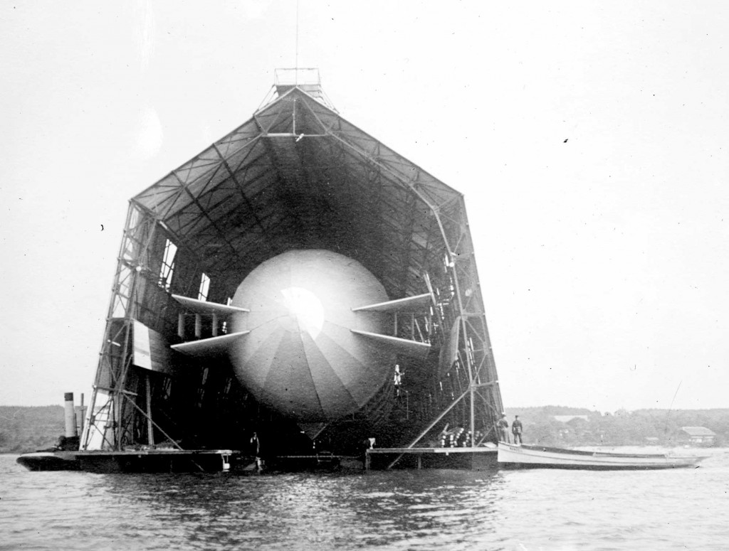 Early zeppelin under construction at floating hangar on the Bodensee. (Possibly LZ-3 in 1906 due to horizontal stabilizers and windows in hangar.)